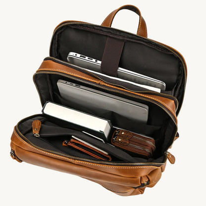 Brown leather backpack with compartments containing electronic devices on a white background
